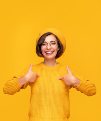 Cheerful woman in yellow clothes pointing at herself