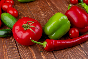 side view of fresh vegetables ripe tomatoes cucumbers red chili pepper and colorful bell peppers on wooden rustic background