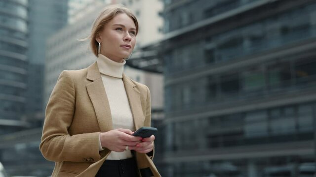 Business woman walking on street with smartphone in hands