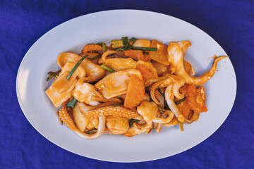 Thai Stir Fried Squid with Salted Egg Yolk served on blue table.