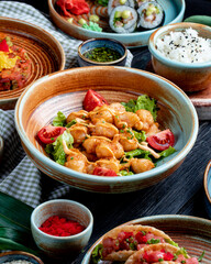 side view of fried chicken with tomatoes and sauce on lettuce on a plate on rustic background