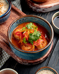 side view of fried shrimps with vegetables and spicy sauce in a bowl on wooden board on rustic background