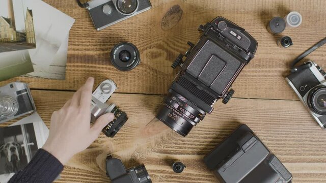 Top Down Shot of a Persons Hands Placing Vintage Film Camera On Table