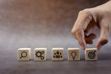 Business strategy development concept, hand stack woods block step on table with icon business strategy and action plan.