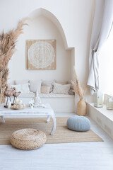 daylight through a huge panoramic window illuminates the cozy oriental interior of the room in...