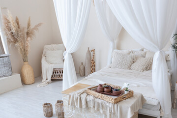 daylight through a huge panoramic window illuminates the cozy oriental interior of the room in beige colors with wicker furniture and authentic elements