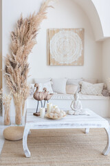 daylight through a huge panoramic window illuminates the cozy oriental interior of the room in beige colors with wicker furniture and authentic elements