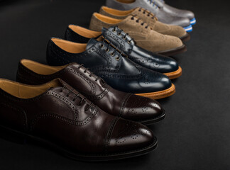 A pair of classic perforated shoes in a row. Showcase with new shoes. Leather shoes on a black background. Diagonal