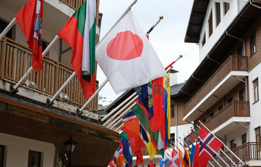 Many national flags of different states hang and blowing on building. Worldwide. International Flags are flying on building. Japanese, Norwegian, Bulgarian Flags. - obrazy, fototapety, plakaty