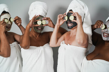Multigenerational women having fun wearing face beauty mask with cucumbers on their eyes - Skin care therapy - Main focus on caucasian female face