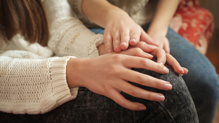 Closeup of teenage girl stroking her friend's hands. Friends support and teenager depression