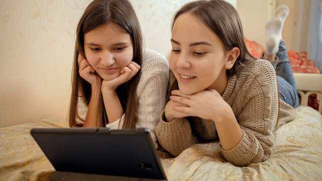 Two teenage girls chatting during educational video conference. Remote studying and communication from home