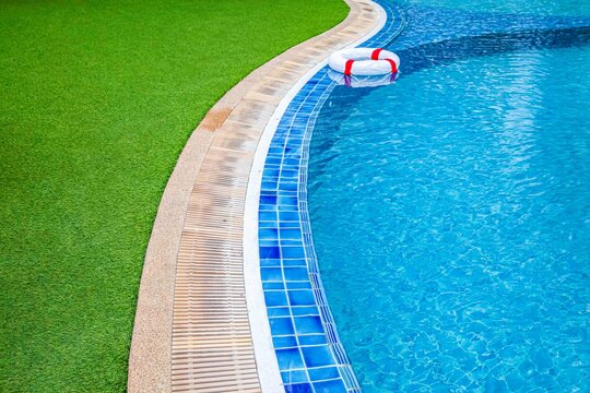 Wide swimming pool and green artificial turf inside the villa