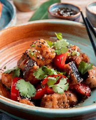 side view of vegetable salad with fried eggplant tomatoes  herbs and sesame in a bowl served with soy sauce on wooden background