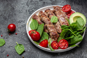 Ketogenic diet, grilled sausages minced meat wrapped in bacon with with spinach, avocado and cherry tomato. chevapchichi or Kofta kebab, Keto paleo diet menu
