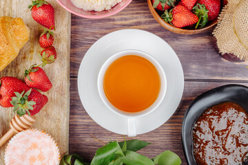 top view of a cup of tea with fresh ripe strawberries  jam and cottage cheese on wooden rustic background