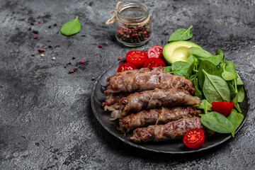 chevapchichi or Kofta kebab, Bacon wrapped minced meat with spinach, avocado and cherry tomato, Healthy fats, clean eating for weight loss. Keto paleo diet menu, top view