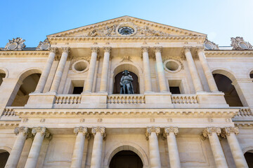 Low angle view of the southern facade of the court of honor of the Hotel des Invalides in Paris, France, with the statue of Napoleon Bonaparte on the balcony