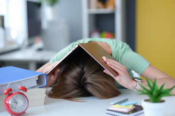 Tired young woman lies on table on head with laptop