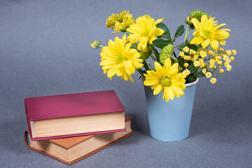 Yellow flowers and books on gray background.