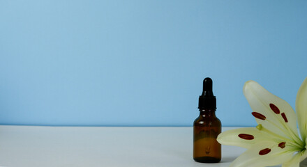 brown glass bottle with cosmetic oil and lily flowers on a blue background.