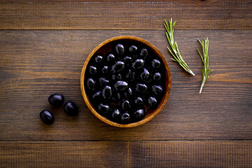 Wooden bowl of pickled black olives, top view