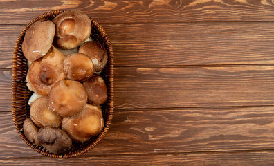 top view of fresh mushrooms in a wicker basket on wooden rustic background with copy space