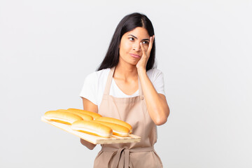 pretty hispanic chef woman feeling bored, frustrated and sleepy after a tiresome and holding a tray...