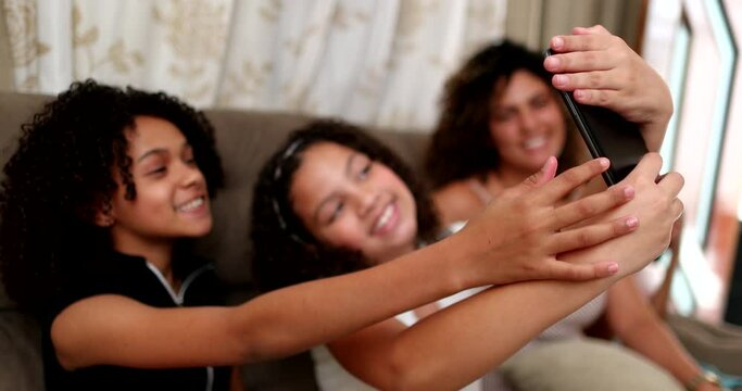 Two little girls taking selfie with cellphone at home together, children using smartphone