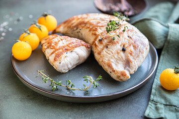 Grilled chicken or turkey breast with cherry tomatoes and thyme on a ceramic plate.