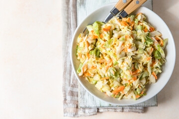 Coleslaw. Salad made of shredded white cabbage, grated carrot and rhubarb with orange mayonnaise dressing in white bowl. Top view.