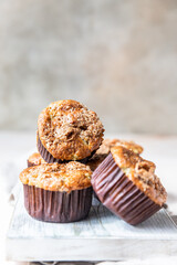 Tasty breakfast muffins with oat crumbs topping on white cutting board, light concrete background.