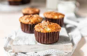 Tasty breakfast muffins with oat crumbs topping on white cutting board, light concrete background.