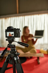 Front view of young woman demonstrating new laptop, unfocused