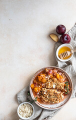 Ceramic plate with tasty plum crumble dessert served with vanilla ice cream and herbs. Top view....