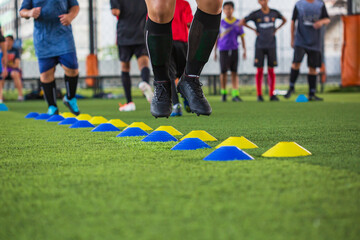 Obraz premium Soccer ball tactics on grass field with barrier for training children jump skill