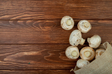 Fototapeta na wymiar top view of fresh mushrooms scattered from a sack on rustic wooden background with copy space