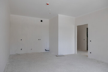 construction of a residential building. The interior of the apartment without finishing in gray tones. Concrete floor.