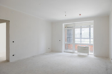 construction of a residential building. The interior of the apartment without finishing in gray tones. Concrete floor.