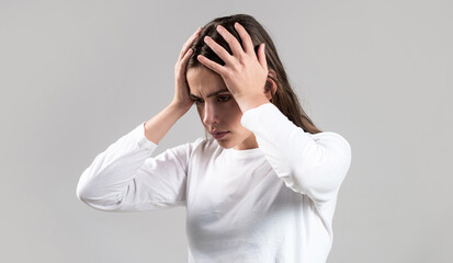 Brunette woman touching her temples feeling stress, on gray background. Woman suffering from headache desperate, stressed because pain and migraine. Woman with hard headache holding hands on head
