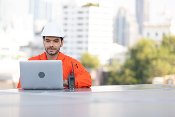 engineer or technician using laptop computer on solar panels on the top of the roof