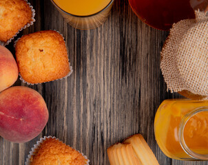 top view of fresh peaches with muffins cookies glass of peach juice and peach jam in a glass jar on rustic wooden background with copy space