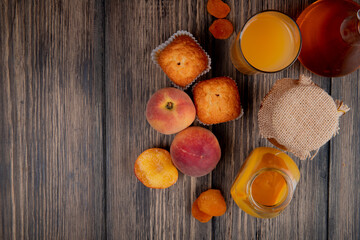 top view of fresh peaches with muffins cookies glass of peach juice and peach jam in a glass jar on rustic wooden background with copy space