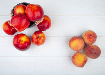 top view of fresh ripe nectarines in a small bucket and fresh peaches on white background