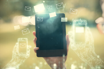 Double exposure of envelop icon hologram and woman holding and using a mobile device. E-mail...