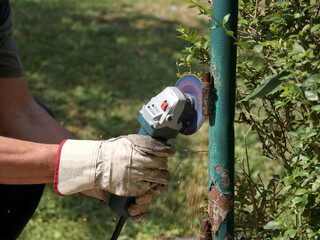 Worker with a grinder cuts an old hinge