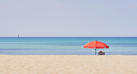 Summer concept. Red umbrella, beach and blue sea on a beautiful sunny day