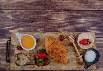 top view of fresh ripe strawberries with croissant honey and cookie cutters on a wooden  cutting...