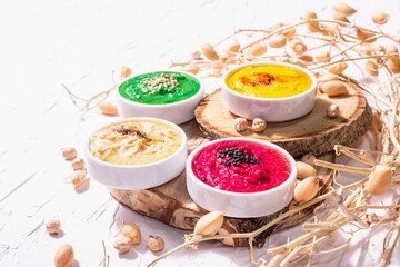 Various hummus dips, the flat lay of hummus in different colors with spinach, beetroot, turmeric and vegetables