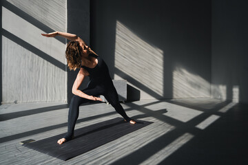 Young woman practicing yoga poses in an urban background on sunny day